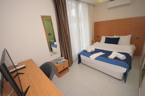 a bedroom with a bed and a desk with a computer at Saatlı Hotel in Çeşme