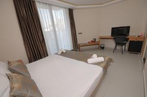 a hotel room with a bed and a desk and a television at Saatlı Hotel in Çeşme