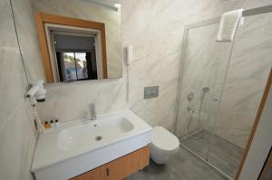 a bathroom with a sink and a shower and a toilet at Saatlı Hotel in Çeşme