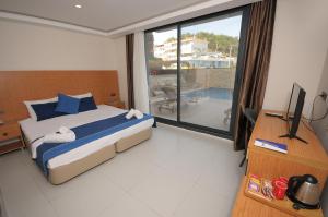 a bedroom with a bed and a large window at Saatlı Hotel in Çeşme