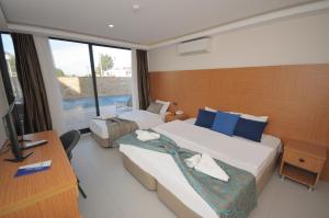 a hotel room with two beds and a desk and a television at Saatlı Hotel in Çeşme