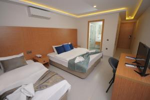 a hotel room with two beds and a television at Saatlı Hotel in Çeşme
