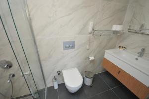 a bathroom with a toilet and a sink and a shower at Saatlı Hotel in Çeşme