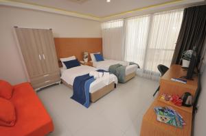 a hotel room with two beds and a couch at Saatlı Hotel in Çeşme