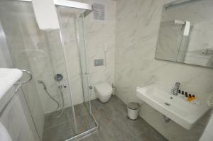 a bathroom with a shower and a sink and a toilet at Saatlı Hotel in Çeşme