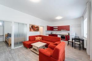 a living room with a red couch and a kitchen at Apartment Yogiam in Slavkov u Brna