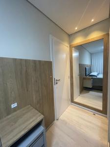 une salle de bains avec un miroir et une chambre avec un lit dans l'établissement Studio 703 - Ravenna Residence, à Itajaí 9 autres photos