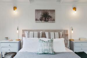 Una cama con almohadas blancas y un cuadro en la pared. en Apollo Bay Beach Hut ~ Wifi ~ Opposite The Ocean, en Apollo Bay 32 fotos más