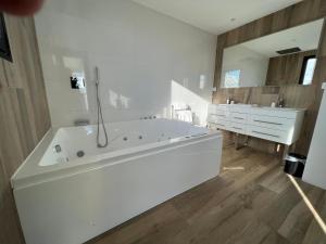 un ampio bagno bianco con vasca e lavandino di VILLA MIAMI a Les Issambres