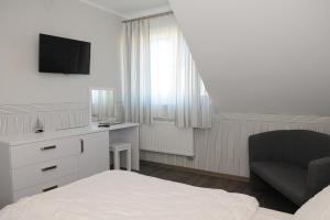 1 dormitorio con 1 cama, 1 silla y TV en Pension Villa Karmelia, en Darłówko