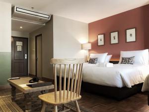 a bedroom with a large bed and a wooden chair at The Raintree Hotel Chiang Mai in Chiang Mai