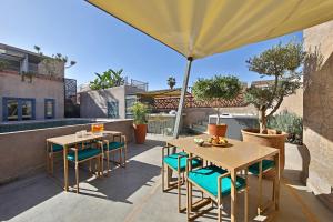 een patio met 2 tafels en stoelen en een parasol bij Riad Dar One in Marrakesh