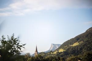 a church in a valley with mountains in the background at ALPIANA - green luxury Dolce Vita Hotel in Vollan