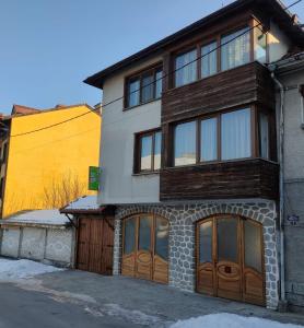 ein Haus mit Holztüren und einem gelben Gebäude in der Unterkunft Guest Rooms Grachenovi in Bansko