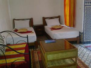 Habitación con 2 camas y mesa. en Riad Azrou, en Azrou