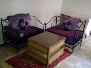 - deux chaises et une table basse dans le salon dans l'établissement Riad Azrou, à Azrou
