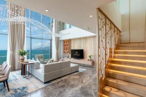a living room with a couch and a tv at Fleur de Lys Hotel Quy Nhon in Quy Nhon