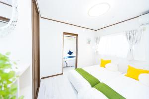 a white bedroom with yellow pillows and a large window at Awaji Garden House in Shinmura in Sumoto