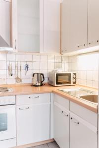 een keuken met witte kasten en een magnetron bij Apartment-EG-07 in Darmstadt