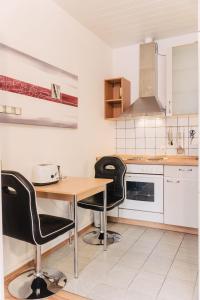 une cuisine avec une table en bois et des chaises noires dans l'établissement Apartment-EG-07, à Darmstadt