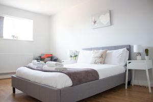 Schlafzimmer mit einem Bett mit weißer Bettwäsche und Kissen in der Unterkunft Large 1st Floor Open Plan Apartment in Loughborough