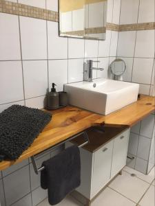 a bathroom with a white sink and a wooden counter at Les Gonies - Amande in Mauroux