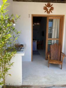 a patio with a wooden chair and a table at Flat Pitaya - Cond. Morada da Praia in Bertioga