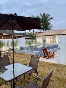 a table and chairs with an umbrella in front of a house at Flat Pitaya - Cond. Morada da Praia in Bertioga