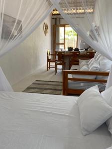 een slaapkamer met 2 bedden en een eetkamer met een tafel bij Flat Pitaya - Cond. Morada da Praia in Bertioga