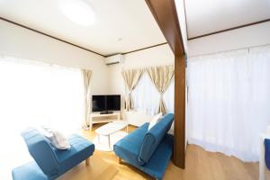 a living room with blue chairs and a tv at Awaji Garden House in Shinmura in Sumoto
