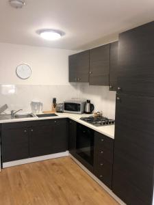 cocina con armarios negros y horno con fogones en 2 Bedroom Large First Floor Apartment with FREE Parking, en Loughborough