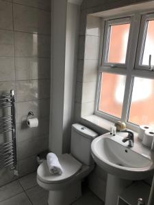 a bathroom with a toilet and a sink and a window at 2 Bedroom Large First Floor Apartment with FREE Parking in Loughborough