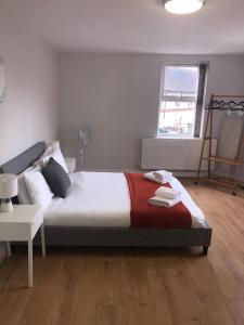 a bedroom with a bed with a red blanket and a window at 2 Bedroom Large First Floor Apartment with FREE Parking in Loughborough