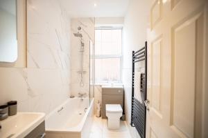 a bathroom with a tub and a toilet and a sink at Deluxe Modern 1&2 Bed Apartments Near Brighton Beach & Station in Brighton & Hove
