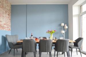 uma sala de jantar com paredes azuis e uma mesa e cadeiras de madeira em Traumkrone Ferienwohnungen - Wiesengrün em Schortens