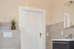 a bathroom with a white door and a sink at Traumkrone Ferienwohnungen - Wiesengrün in Schortens