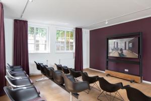 une salle d'attente avec des chaises et une télévision à écran plat dans l'établissement Hotel Upstalsboom Langeoog, à Langeoog