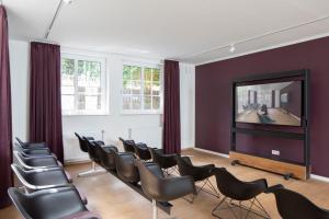 a waiting room with chairs and a flat screen tv at Hotel Upstalsboom Langeoog in Langeoog