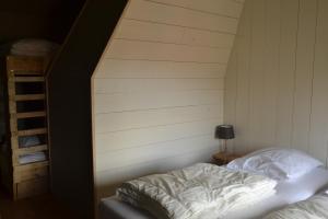 Bett in einem Zimmer mit einer weißen Wand in der Unterkunft Vakantiewoning Boerderij De Gerrithoeve in Oisterwijk
