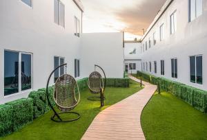 Fandoi的住宿－Swiss-Belhotel Cendrawasih, Biak，建筑草上带椅子的走道