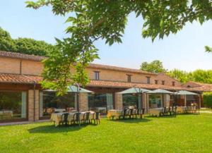 a building with tables and chairs in the grass at Hotel La Foresteria in Abbadia di Fiastra