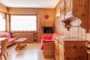 a kitchen with wooden cabinets and a living room at Ca' Milijera in Cortina dʼAmpezzo