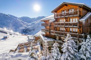 a ski lodge in the mountains with snow covered trees at Chalet Hotel Kaya in Les Menuires