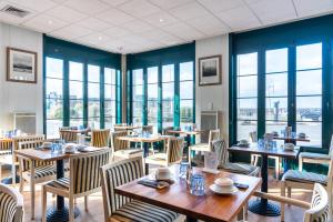 un ristorante con tavoli e sedie in legno e finestre di SOWELL HOTELS Le Beach a Trouville-sur-Mer