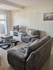 uma sala de estar com um sofá de couro e uma televisão em 15 Isikhulu em Umdloti