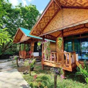 a large wooden house with chairs in the yard at Kohmook Happy time Bungalow in Koh Mook