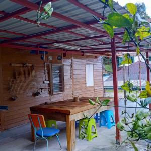 una mesa de madera y sillas bajo una pérgola en The Rustique Guest House en Tanah Rata