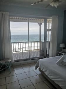 a bedroom with a bed and a view of the ocean at 21 Camarque in Umdloti