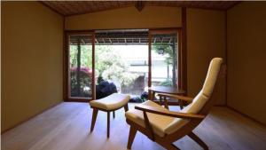 Habitación con 2 sillas, mesa y ventana en Atami Sekitei, en Atami