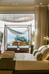 a bedroom with a bed with a view of the ocean at Avgoustos Suites Naxos in Naxos Chora